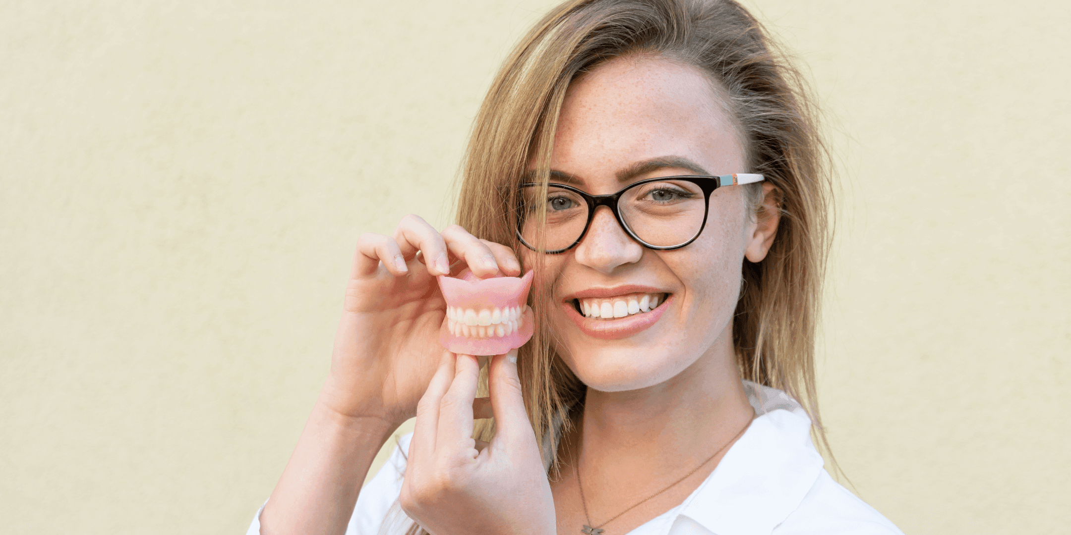 Dentist holds dentures in her hands, smiling
