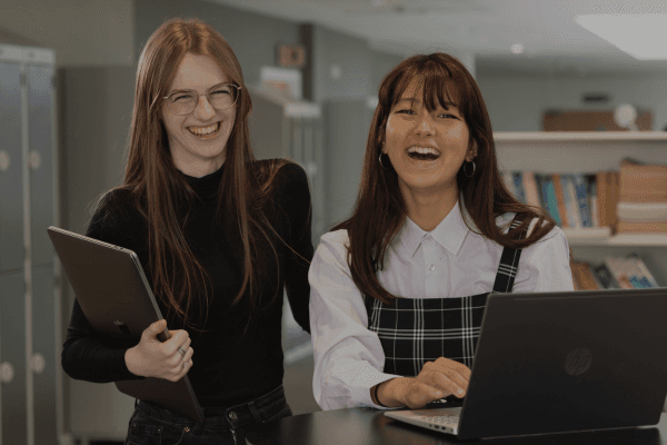 Two girls on work experience laughing at the camera.